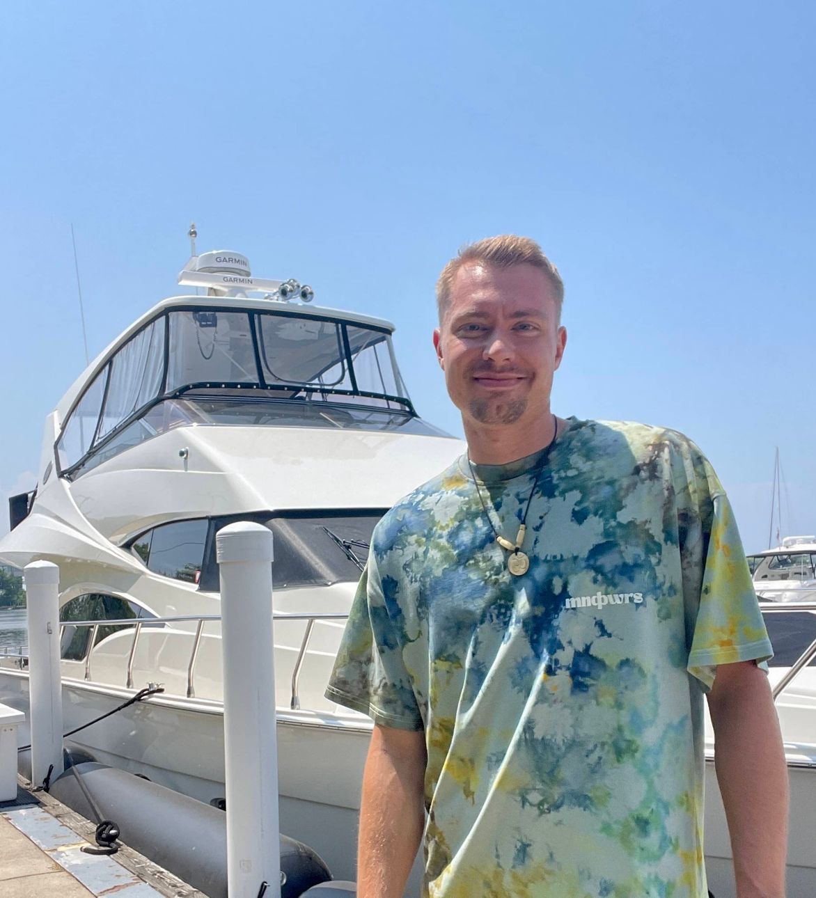 clayton in front of a boat smiling
